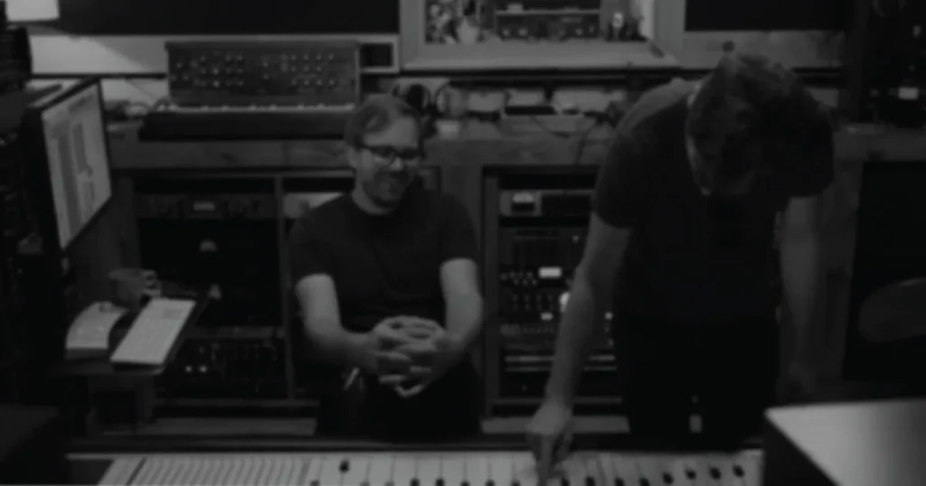 Black-and-white photo of two engineers at a studio console, the cover of Soundfly's Faders Up I course