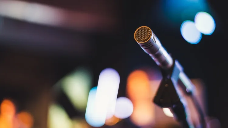 A studio microphone in front of colourful lights, the image for The Complete Mixing Masterclass on Udemy