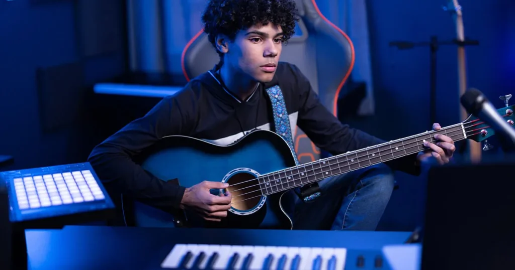 Full Sail University music production image of a young musician playing bass in a home studio