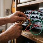 A producer's hands plugging a yellow patch cable into a modular synth, with red and green cables already patched, like the audio, parameter and event cables in FL Studio's Patcher