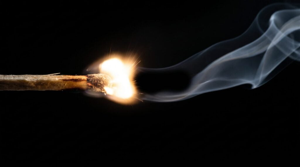 A match bursting into flame with its smoke starting a short gap behind the flash, like a snare hit followed by pre-delayed reverb