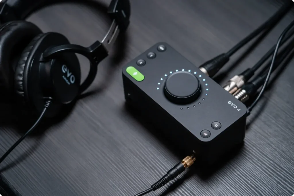 Audient EVO 4 audio interface on a desk with its large control knob and headphones plugged in
