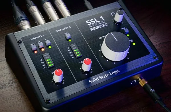 SSL 1 audio interface on a desk with cables plugged in, showing its gain knob, level meters and large monitor knob