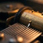 Close-up of a music box mechanism: a brass pin on the turning cylinder plucks one steel tooth of the comb in warm amber light, a melody played one note at a time